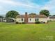 A yellow home with a brick chimney and a spacious, well-maintained backyard with a carport is presented at 3537 Heather Ln, Gastonia, NC 28056