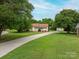 Photo shows a single-story home with red shutters, a long driveway, a carport, and mature trees in a grassy lawn at 3537 Heather Ln, Gastonia, NC 28056