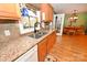 Well-lit kitchen featuring granite countertops, wood cabinets, and stainless steel sink overlooking the dining room at 4646 River Run Cir, Hickory, NC 28602