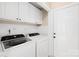 Clean laundry room with modern washer and dryer, storage cabinets, and white door at 4809 Mossy Cup Ln, Monroe, NC 28110