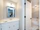 A half bathroom with a large vanity, white cabinets, and a decorative mirror at 4925 Cedar Forest Dr, Charlotte, NC 28226