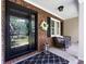 Close-up of the front door and porch area, showcasing a decorative wreath, seating, and charming brickwork at 4925 Cedar Forest Dr, Charlotte, NC 28226