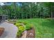 Expansive backyard featuring lush landscaping, a stone walkway, and mature trees at 516 Amanda Dr, Weddington, NC 28104