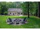 Inviting backyard featuring a stone fire pit with chairs, lush lawn and view of the home's exterior and back patio at 516 Amanda Dr, Weddington, NC 28104