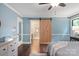 Cozy bedroom featuring light blue walls, a sliding barn door to ensuite, and a ceiling fan at 516 Amanda Dr, Weddington, NC 28104