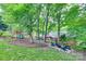 Landscaped backyard featuring a playground, fire pit, seating and mature trees at 6626 Rocky Falls Rd, Charlotte, NC 28211