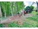 Spacious backyard with lush greenery, large trees, and a wooden playset for children in a serene setting at 6626 Rocky Falls Rd, Charlotte, NC 28211