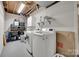 Laundry room with a washer, dryer, utility sink, shelving, storage bins, and an exposed wood ceiling at 6626 Rocky Falls Rd, Charlotte, NC 28211