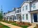 Charming street view of white townhomes with black shutters, well-maintained landscaping and sidewalks at 8102 Jacey Ln # 24, Huntersville, NC 28078