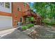 Exterior of brick home featuring a second story deck, patio, and verdant landscaping at 8217 Lansford Rd, Charlotte, NC 28277