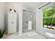 Bright bathroom featuring glass shower, white cabinet for storage, and bright window with trees visible outside at 8217 Lansford Rd, Charlotte, NC 28277