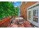 Enjoy outdoor living on this brick home's deck, furnished with a dining table and chairs, shaded by a large umbrella at 8217 Lansford Rd, Charlotte, NC 28277