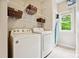 Functional laundry room featuring a modern washer and dryer, with wire shelving for organized storage and a sunlit window at 8217 Lansford Rd, Charlotte, NC 28277