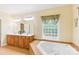 Bathroom featuring a jetted tub, dual sinks, wood cabinets, and tiled floors at 8622 Lower Rocky River Rd, Concord, NC 28025