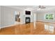 Light-filled living room with hardwood floors, a fireplace and access to the kitchen at 8622 Lower Rocky River Rd, Concord, NC 28025