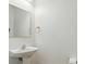 Half bath with pedestal sink, modern mirror, and neutral decor at 9856 Caldwell Depot Rd, Cornelius, NC 28031
