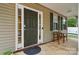 Covered porch with seating for two, decorative shutters, and a dark paneled front door at 9856 Caldwell Depot Rd, Cornelius, NC 28031