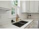 Bright kitchen featuring white cabinets, subway tile backsplash, and a stainless steel sink under a window at 9856 Caldwell Depot Rd, Cornelius, NC 28031