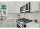 Well-equipped kitchen with stainless steel appliances, including microwave and gas cooktop, and white cabinets at 9856 Caldwell Depot Rd, Cornelius, NC 28031