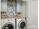 Charming laundry room with light blue cabinets, floral wallpaper, and modern washer and dryer at 9856 Caldwell Depot Rd, Cornelius, NC 28031