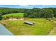 Aerial view showcasing a pond and outbuilding with a green metal roof, surrounded by green landscape at 9950 Foil Rd, Mount Pleasant, NC 28124