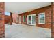 This covered patio features a brick exterior, concrete flooring, and access to the yard via french doors at 9950 Foil Rd, Mount Pleasant, NC 28124