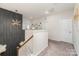 Hallway with geometric accent wall, modern chandelier, plush carpet and white stairway with wood railing at 10045 Carousel Corral Dr, Midland, NC 28107