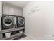 This laundry room features a washer and dryer, gray cabinets and shelving, plus decorative wall art at 10045 Carousel Corral Dr, Midland, NC 28107