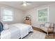 This bedroom features neutral tones, light hardwood floors, bright windows, and a ceiling fan at 1152 Penrose Ln, Charlotte, NC 28217