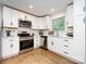 Bright kitchen with white cabinets, stainless steel appliances, and wood-look floors at 1152 Penrose Ln, Charlotte, NC 28217