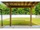 Picturesque backyard featuring a pergola covering a concrete patio with lush green grass and a white fence surrounded by trees at 12923 Plumleaf Dr, Charlotte, NC 28213