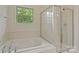 Bright bathroom with a separate shower and soaking tub near a window at 12923 Plumleaf Dr, Charlotte, NC 28213