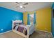 Bedroom with blue and yellow walls, a white bed frame and natural light from the window at 12923 Plumleaf Dr, Charlotte, NC 28213
