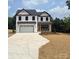 Charming two-story home featuring white siding, black trim, an attached garage, and a covered front porch with stone accents at 1308 Austin Chaney Rd, Wingate, NC 28174