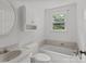 A bathroom featuring a white vanity, toilet, and bathtub with tile surround and a window at 14415 Old Beatty Ford Rd, Gold Hill, NC 28071