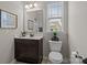 Cozy bathroom featuring a vanity with dark cabinets, a mirror, a toilet and a window at 16034 Rushwick Dr, Huntersville, NC 28078