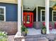 Close-up of the charming front porch featuring red chairs, a vibrant red door, and well-maintained landscaping at 164 Twin Sisters Ln, Mooresville, NC 28117