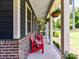 Inviting covered front porch showcasing red chairs and views of the manicured lawn and mature trees at 164 Twin Sisters Ln, Mooresville, NC 28117