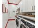 Modern laundry room with updated appliances, white cabinetry, and red accents at 164 Twin Sisters Ln, Mooresville, NC 28117