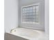 Elegant white bathtub with jacuzzi jets and a glass block window for privacy at 20324 Middletown Rd, Cornelius, NC 28031