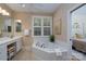Bathroom featuring vanity, soaking tub with white tile surround, and large window at 258 Patterson'S Bridge None, New London, NC 28127