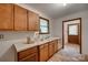A view of a kitchen with wooden cabinets, white countertops, and worn flooring at 2921 Ambrose Dr, Gastonia, NC 28056