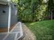 Exterior view of the home, featuring a walkway leading to a large, grassy backyard bordered by lush trees at 3314 Mara Ct, Matthews, NC 28105