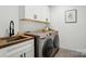 Well-equipped laundry room with stainless steel washer/dryer, sink, and white cabinets at 343 Melbourne Ct, Charlotte, NC 28209