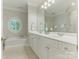 Bright bathroom with a soaking tub, double vanity, and a large mirror with vanity lights at 4026 Barclay Downs Dr, Charlotte, NC 28209