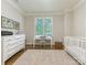 Bright bedroom featuring a white crib, dresser, and desk near a large sunlit window at 4026 Barclay Downs Dr, Charlotte, NC 28209