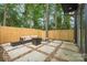 Inviting backyard space with paved patio, outdoor seating, and a wood privacy fence surrounded by mature trees at 411 Granby Cir, Charlotte, NC 28217