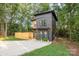 Contemporary home with gray facade, natural wood accents, and a paved driveway amidst a wooded landscape at 411 Granby Cir, Charlotte, NC 28217