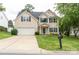 Charming two-story home with a well-manicured lawn and attached garage, painted in neutral beige at 435 Riverwalk Nw Dv, Concord, NC 28027