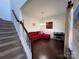 Cozy living room featuring a red sofa, a dark desk, hardwood floors and a staircase at 435 Riverwalk Nw Dv, Concord, NC 28027